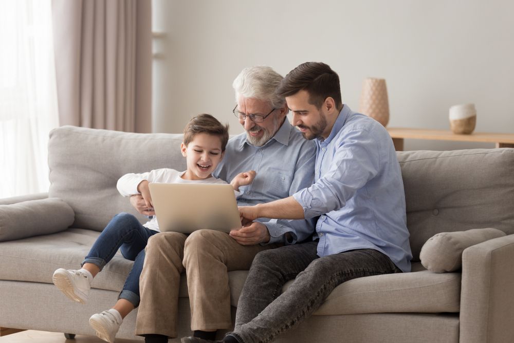 Three Generations Viewing Laptop: Boy, Grandfather, and Father on a Sofa — Shane Kelly Communications in Lennox Head, NSW