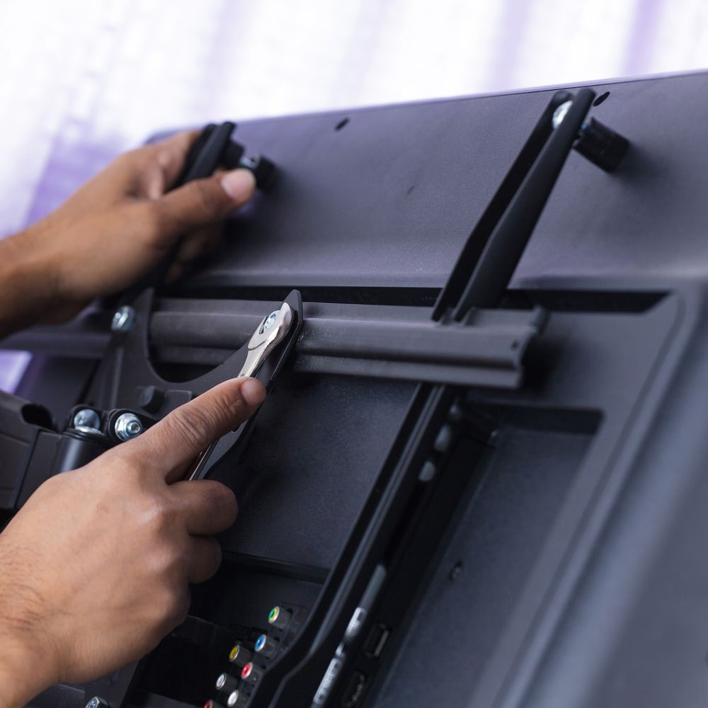Person Using a Wrench to Tighten a Screw on the Back of a TV — Shane Kelly Communications in Lennox Head, NSW
