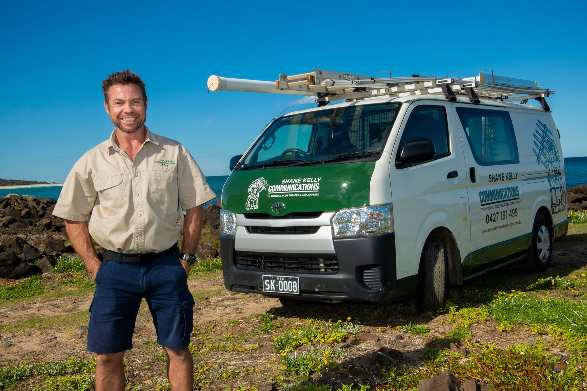 Man in Work Clothes Stands Beside a White Van, on a Coastal Landscape — Shane Kelly Communications in Lennox Head, NSW
