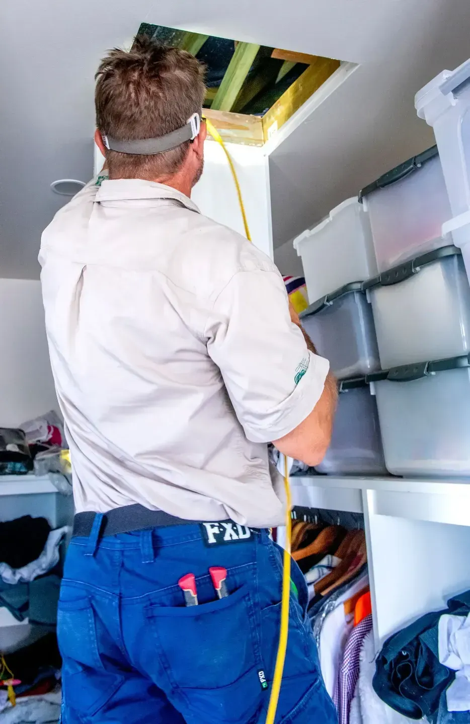 Man in Work Clothes Inspecting an Attic Access. White Closet — Shane Kelly Communications in Lennox Head, NSW