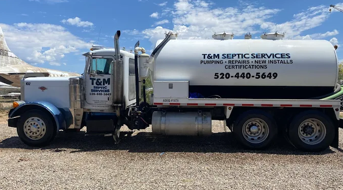 White T&M Septic Services vacuum truck parked on gravel under a blue sky.