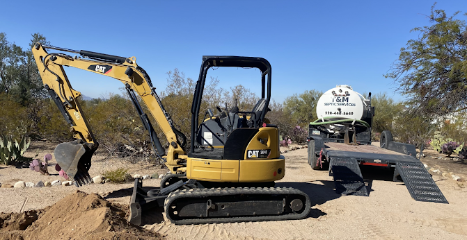 Yellow excavator beside a tanker truck in a dry outdoor worksite under a clear blue sky