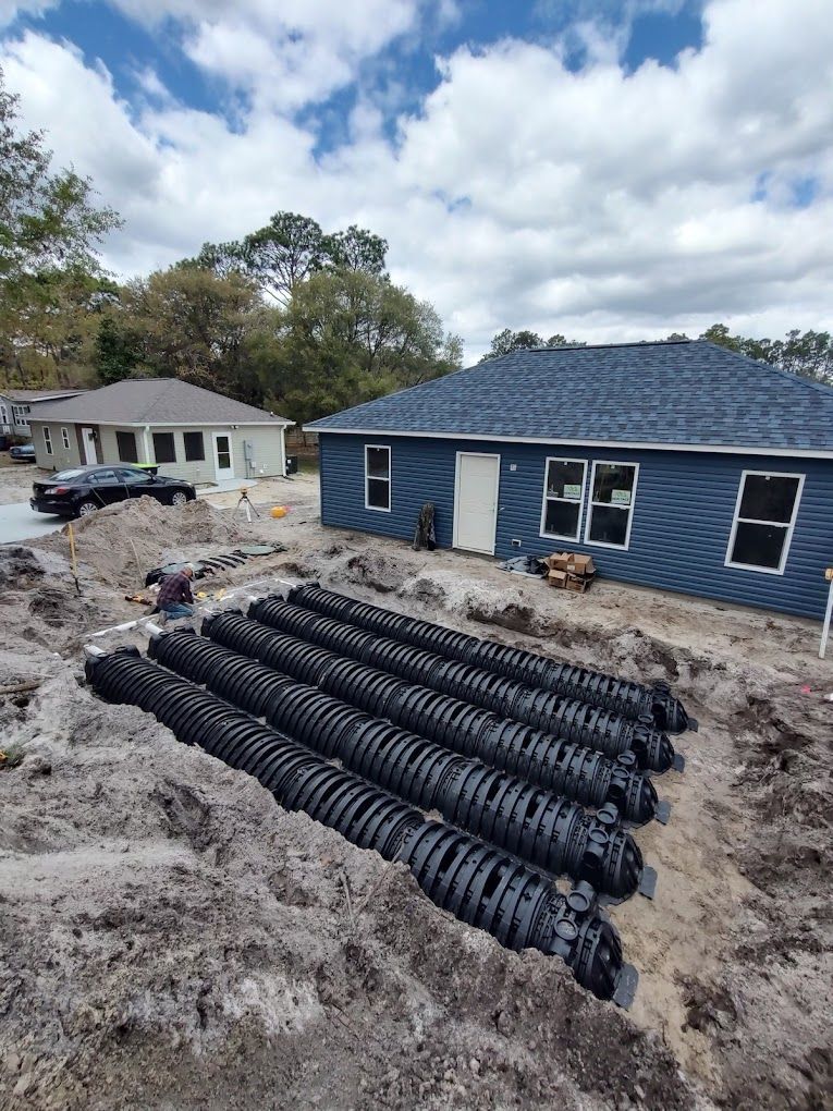 A row of septic tanks are being installed in front of a house.