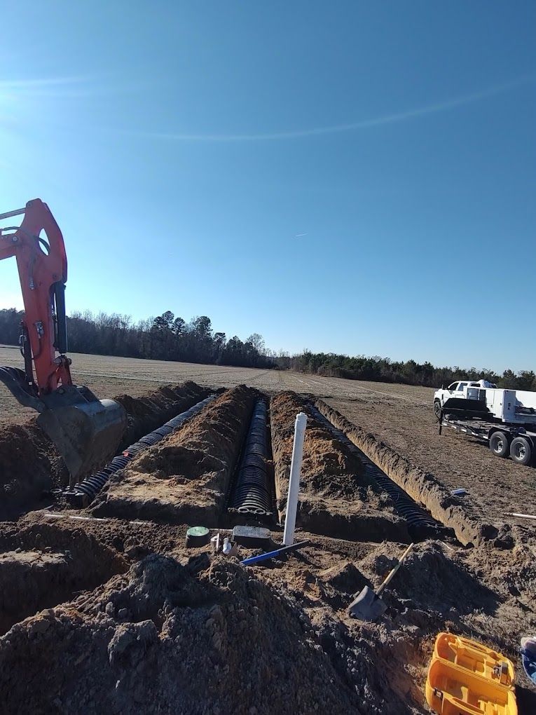 An excavator is digging a hole in the dirt in a field.