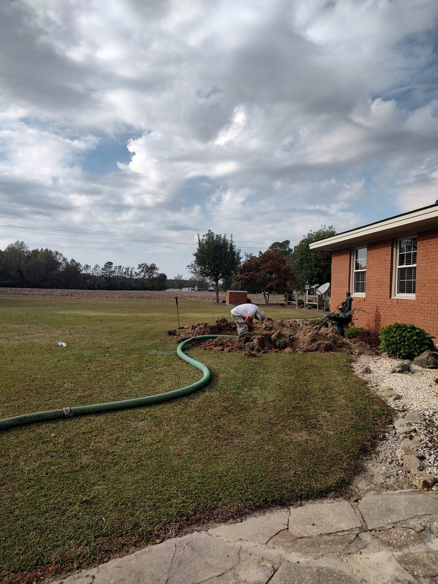 There is a hose in the grass in front of a brick house.