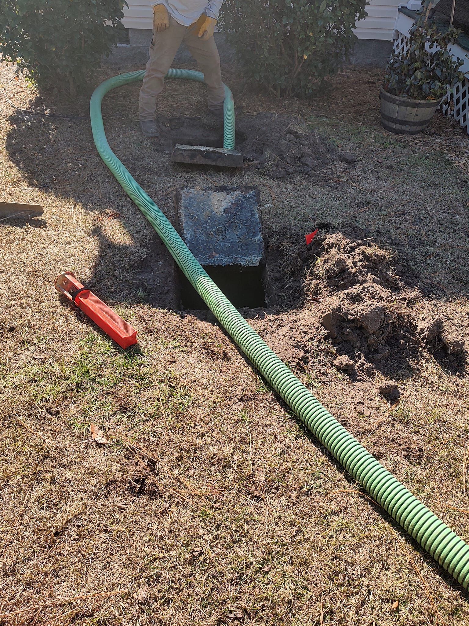 A green hose is being used to pump a septic tank.