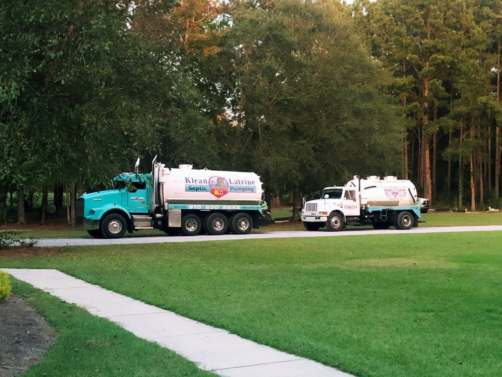 Two septic systems trucks are parked on the side of the road
