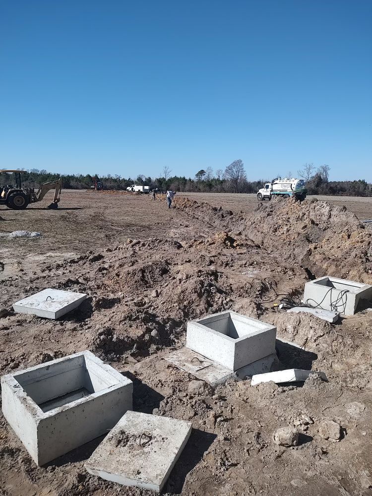 A construction site with a lot of concrete boxes in the dirt.