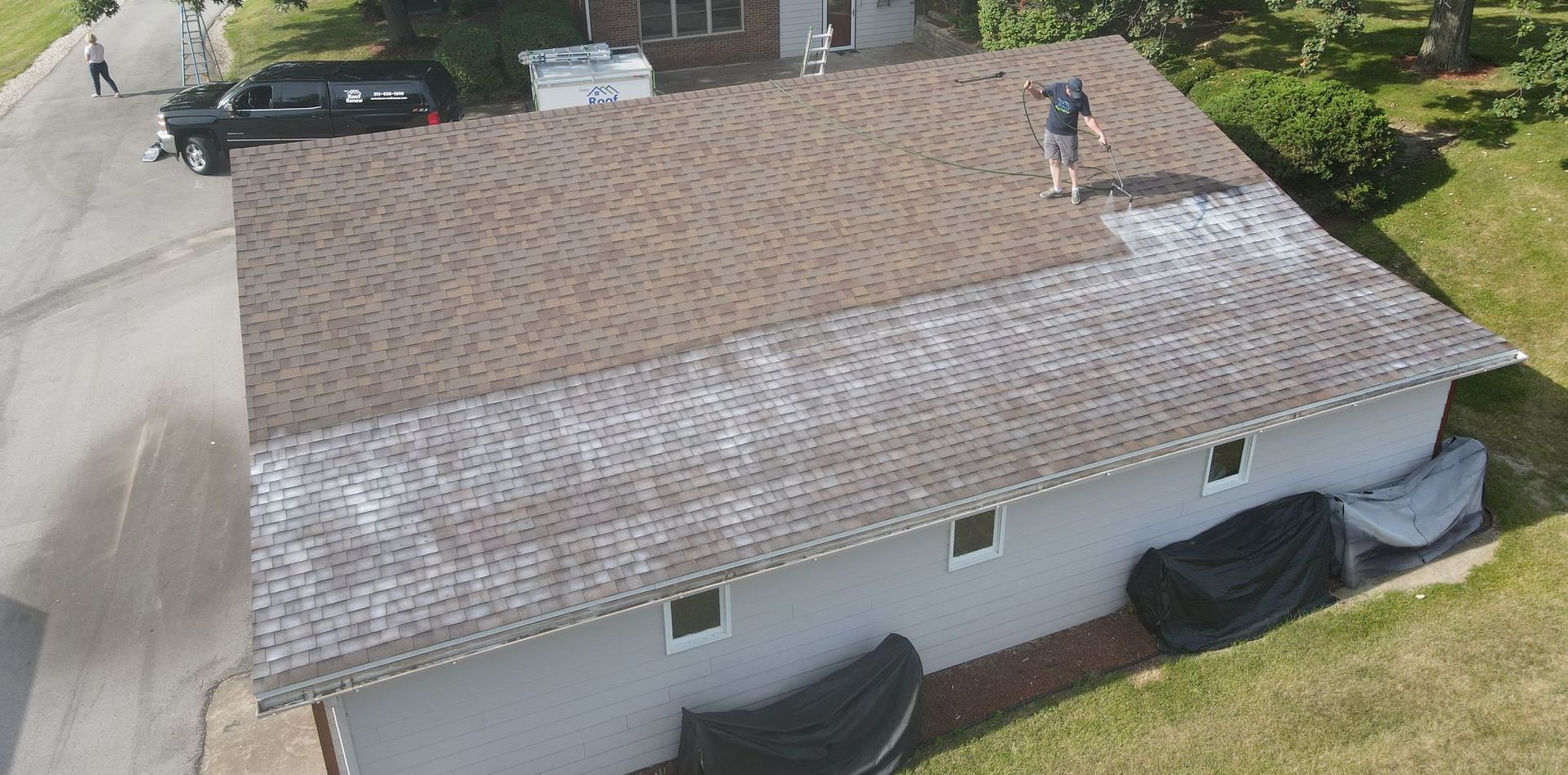 A man is standing on the roof of a house.