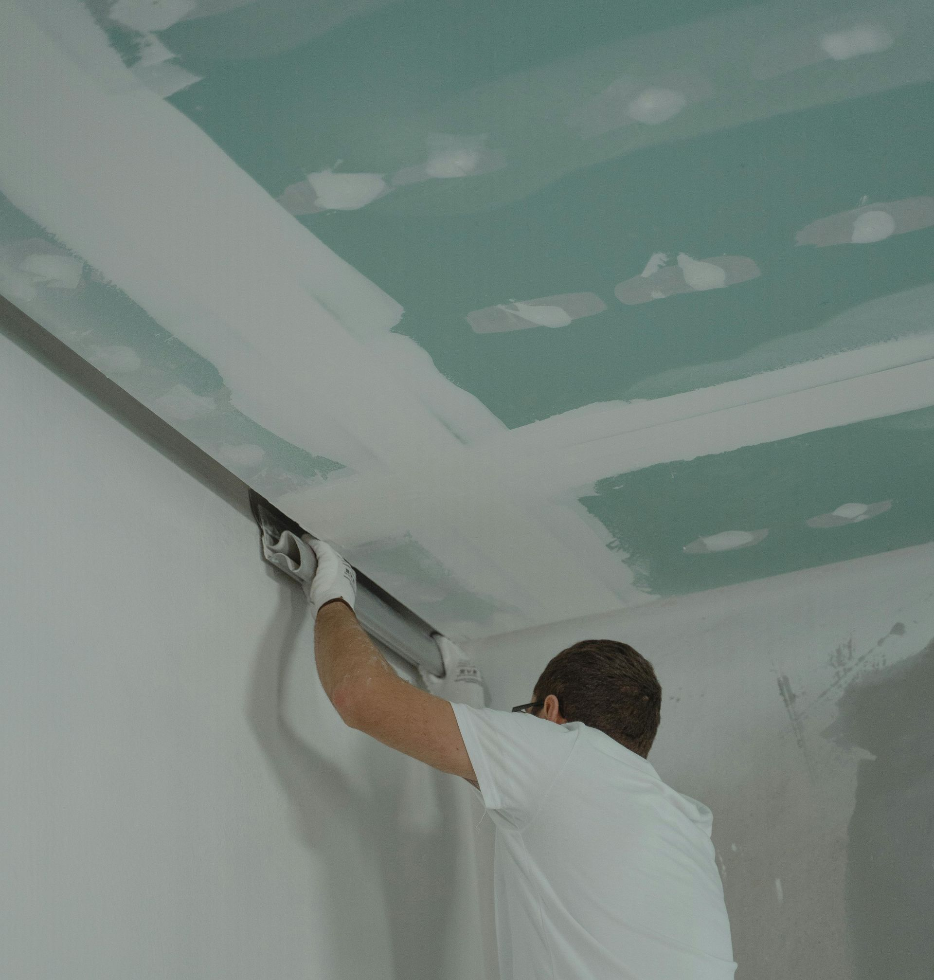 A skilled handyman installing a new light bulb in a recessed ceiling light fixture.