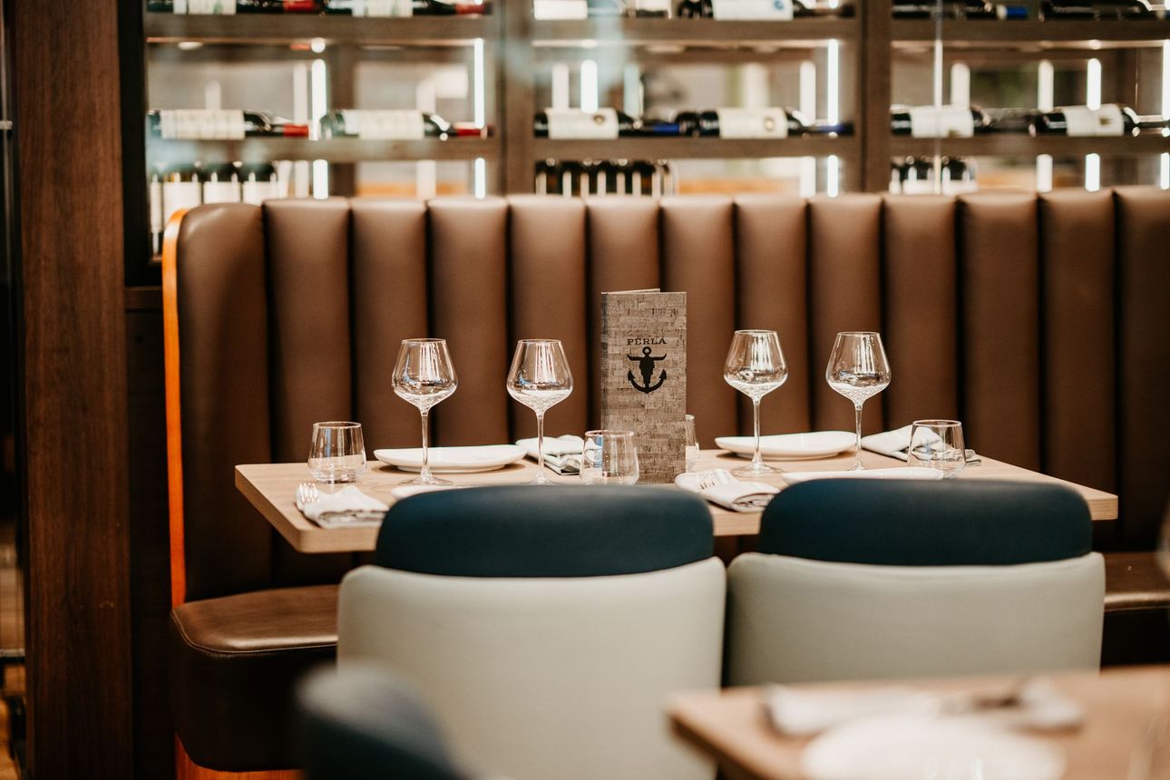 Elegant restaurant booth with a set table, wine glasses, and warm wood-and-leather seating.