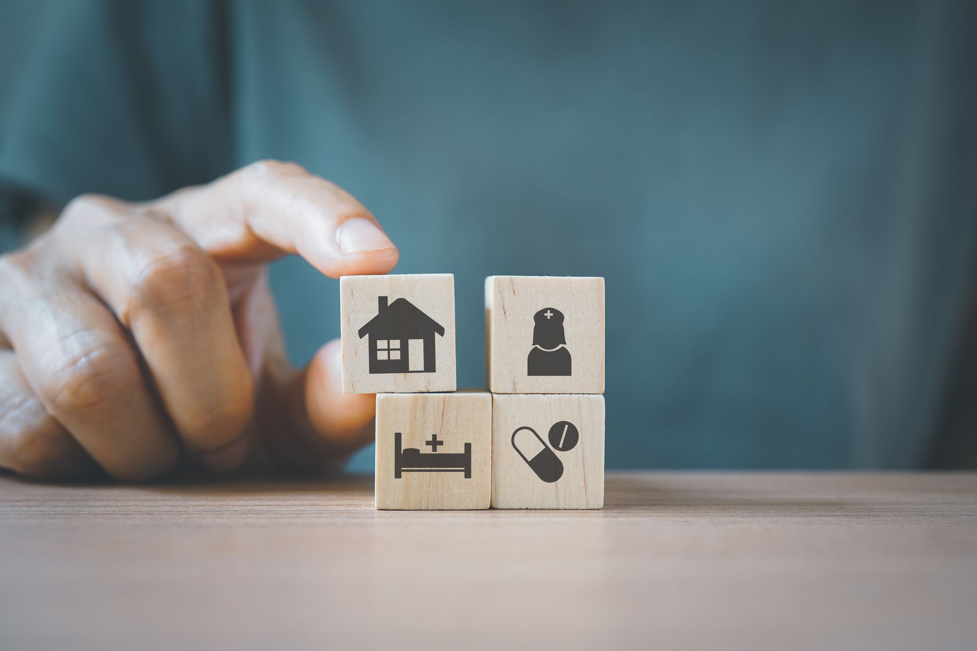 Wooden blocks with home, nurse, and medication icons symbolizing medicare health plans coverage