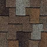 Close-up of overlapping asphalt roofing shingles in varied shades of brown, gray, and black.