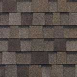 A pattern of overlapping architectural asphalt roof shingles in shades of brown, gray, and tan.