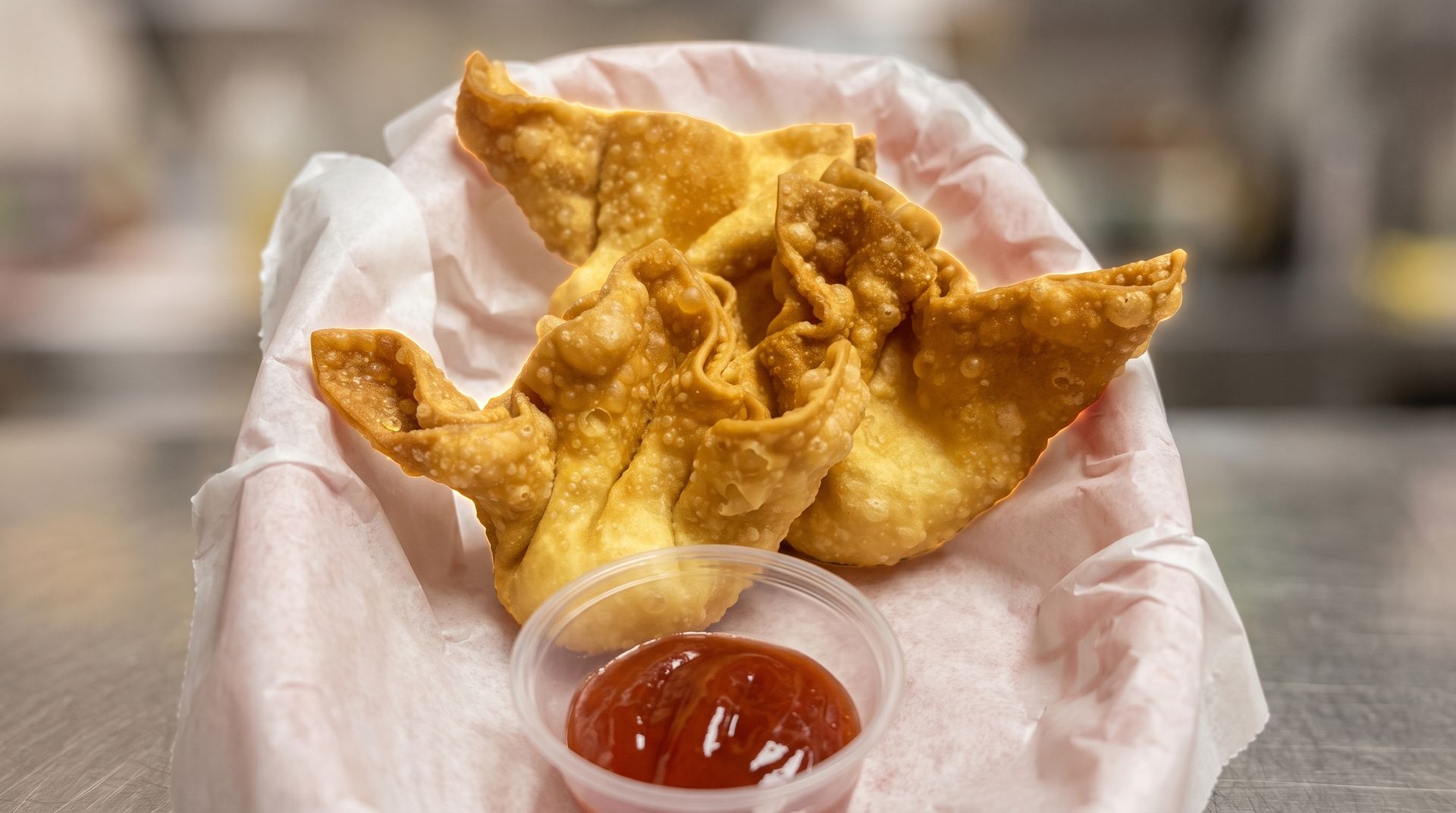 Golden fried wonton chips in a basket with dipping sauce on a table
