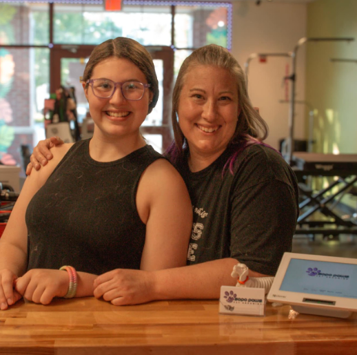 Two women are posing for a picture while sitting at a counter