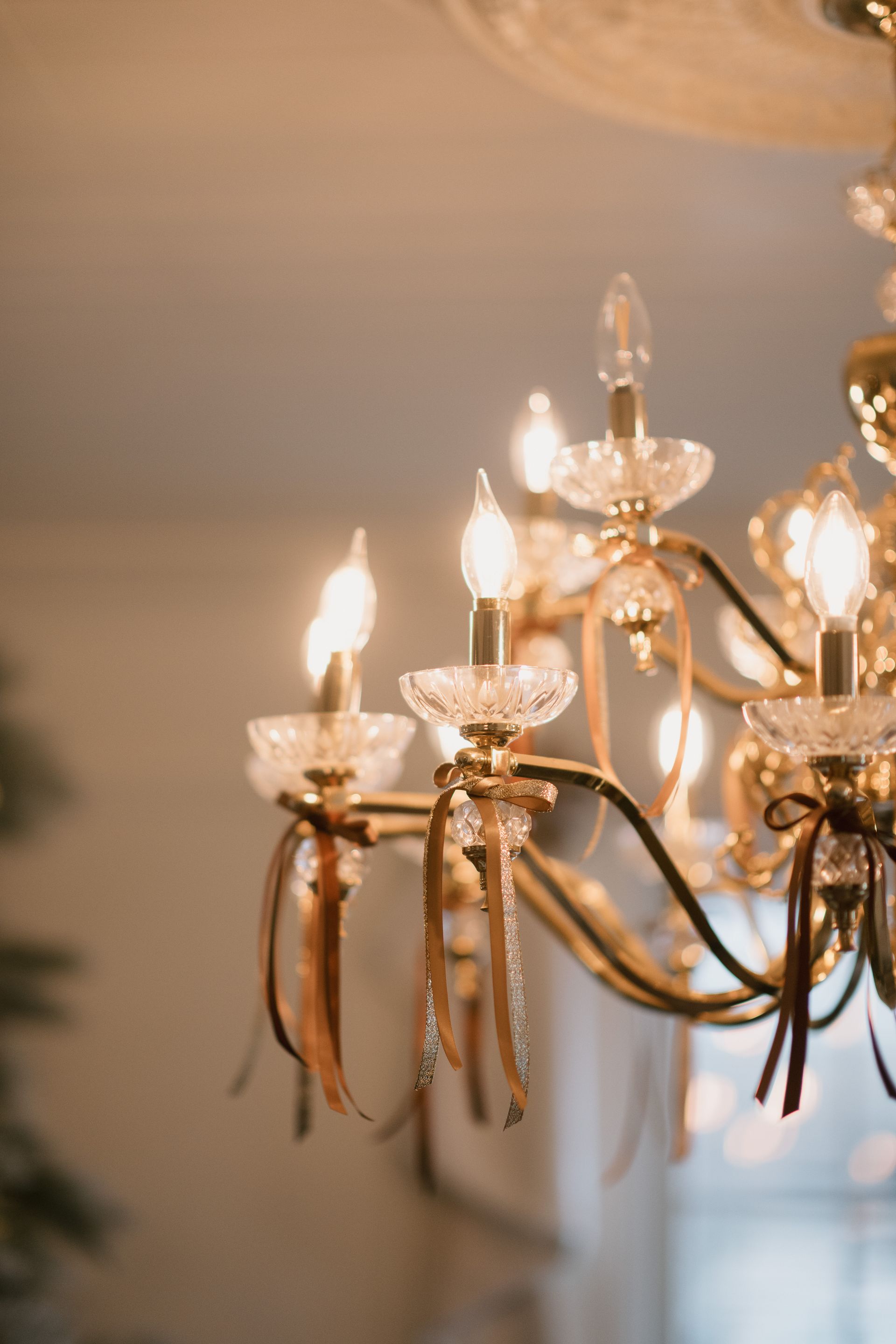 Close-up of a gold chandelier with lit, candle-shaped bulbs, hanging from a white ceiling.