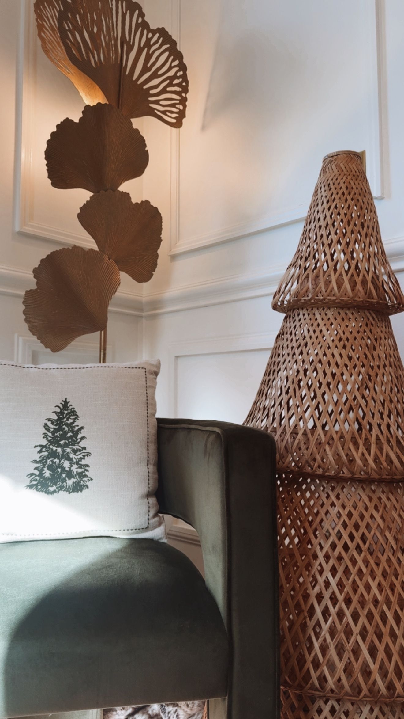 Corner of a room with a decorative woven Christmas tree and a green sofa with a tree-themed pillow.