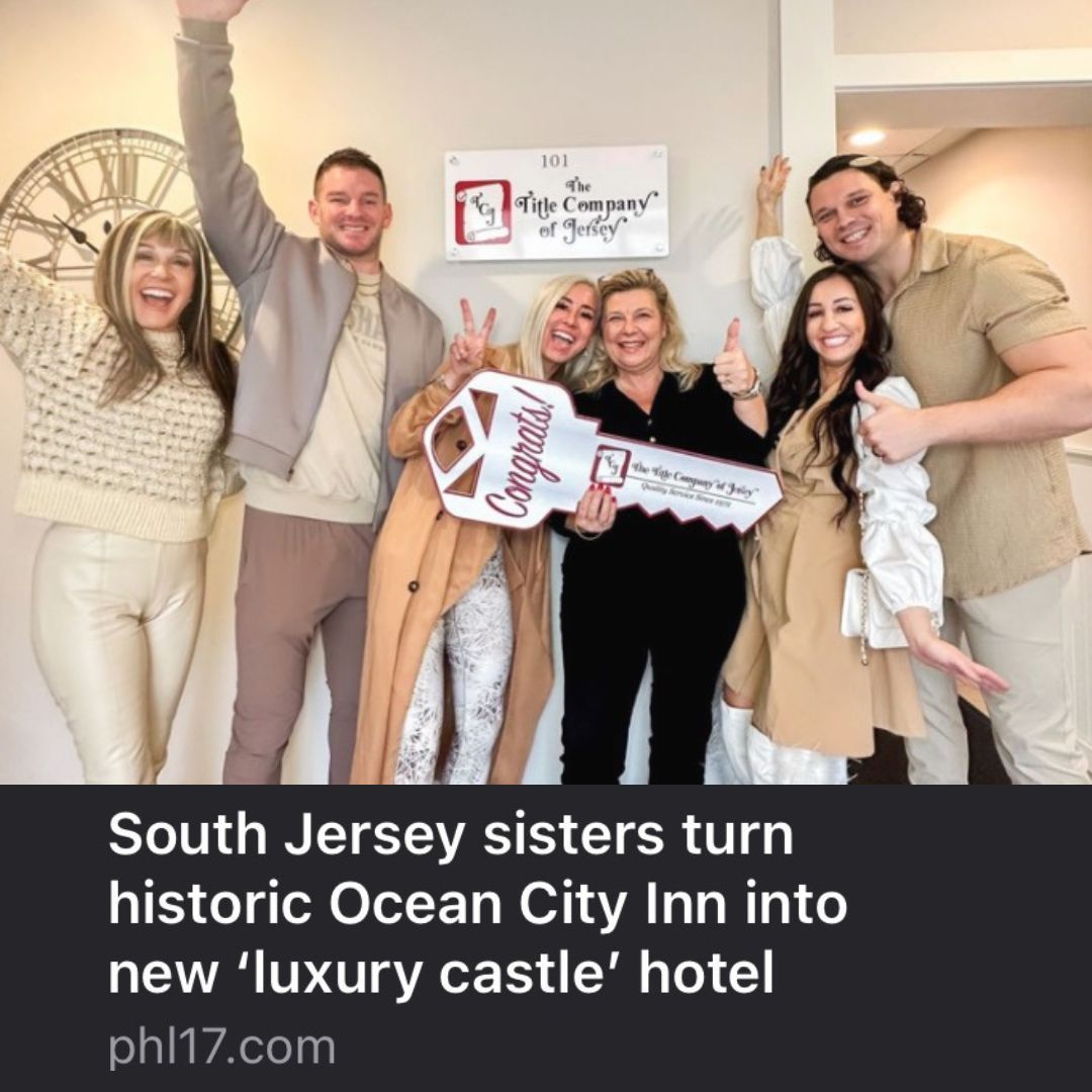 Group of people holding a giant key in front of a sign, celebrating a new hotel.