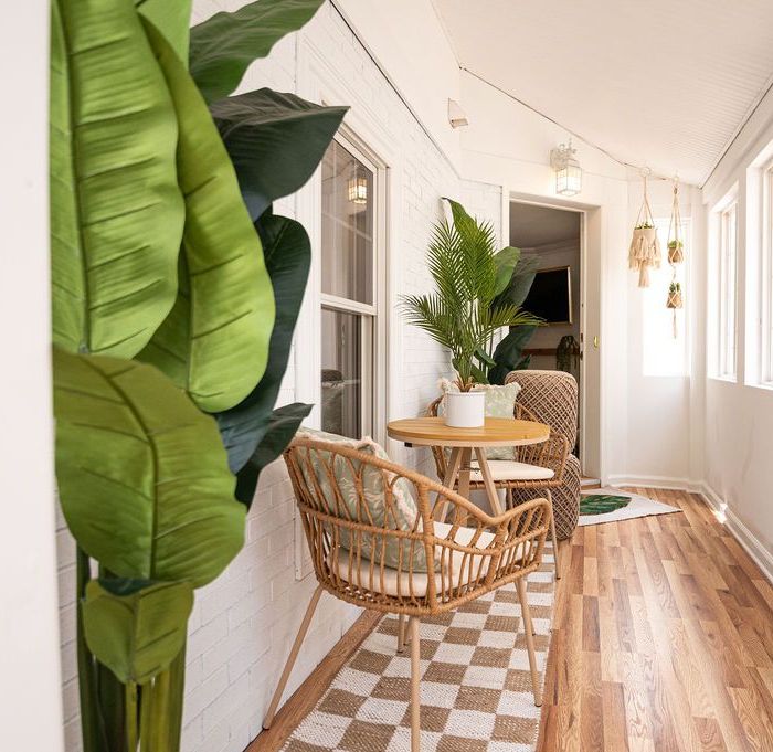 Sunroom with woven chair, small table, and potted plants; light wood floors.