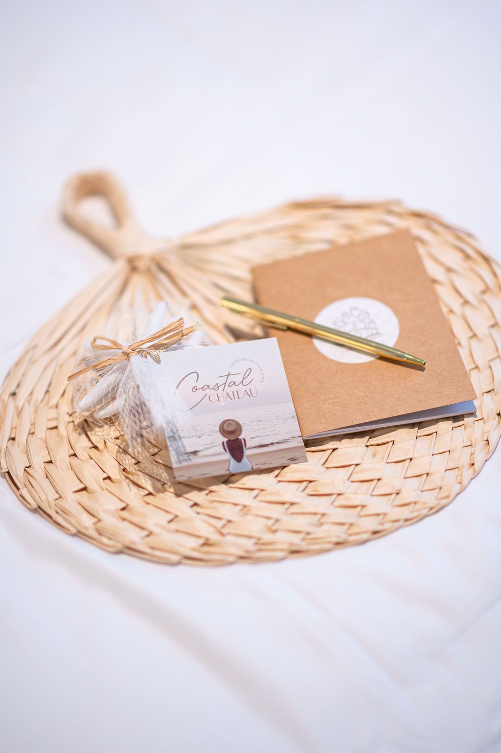 Woven fan with a notepad, pen, and a small stack of cards. The items are on a white surface.