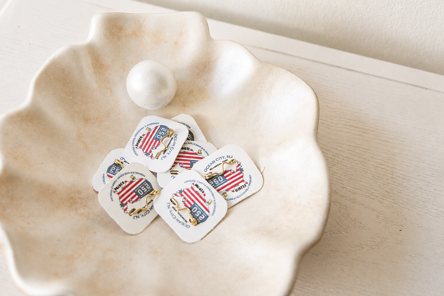 Small white dish with four wrapped candies and a white round object on a beige tabletop