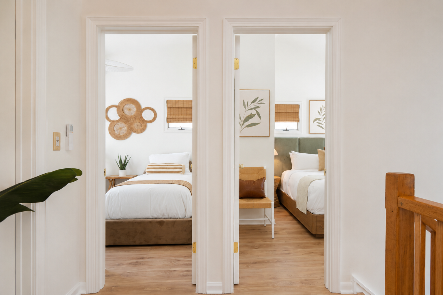 Bright hallway with two open bedroom doorways, white walls, wood floors, and warm natural light