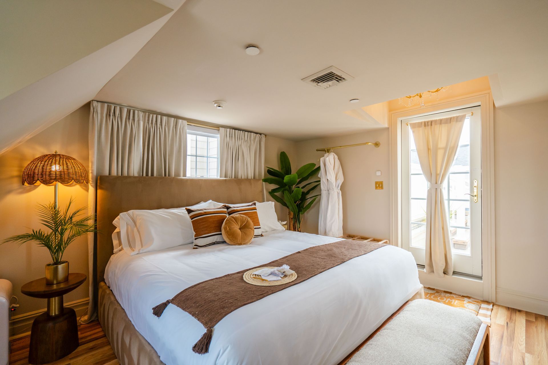 Cozy hotel bedroom with king bed, brown accents, and a balcony.