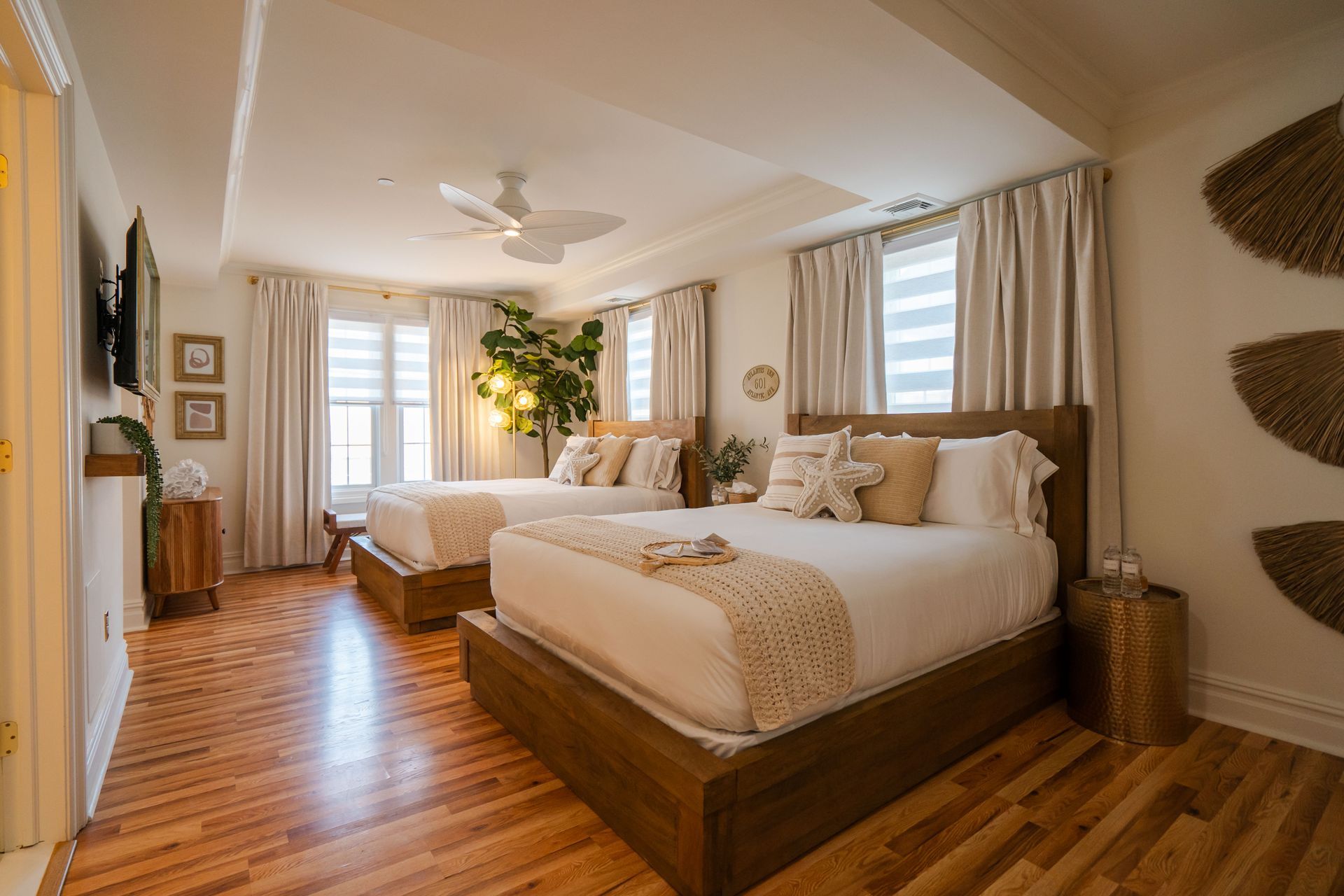 Bedroom with two beds, wood floors, beige walls, and decorative accents.