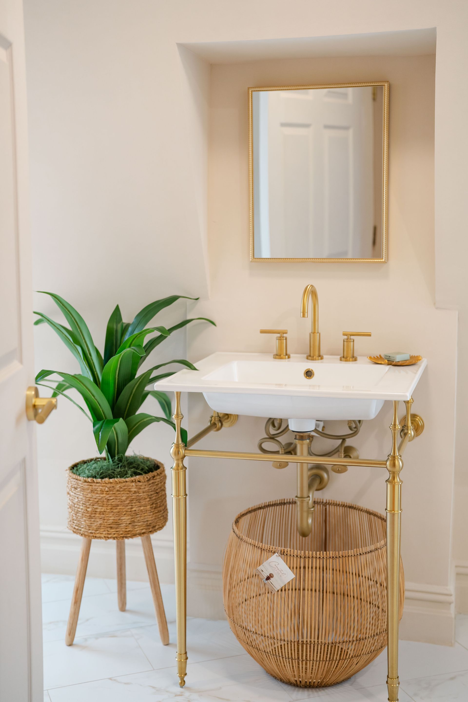 Bathroom with gold fixtures, white sink, and decorative plants.