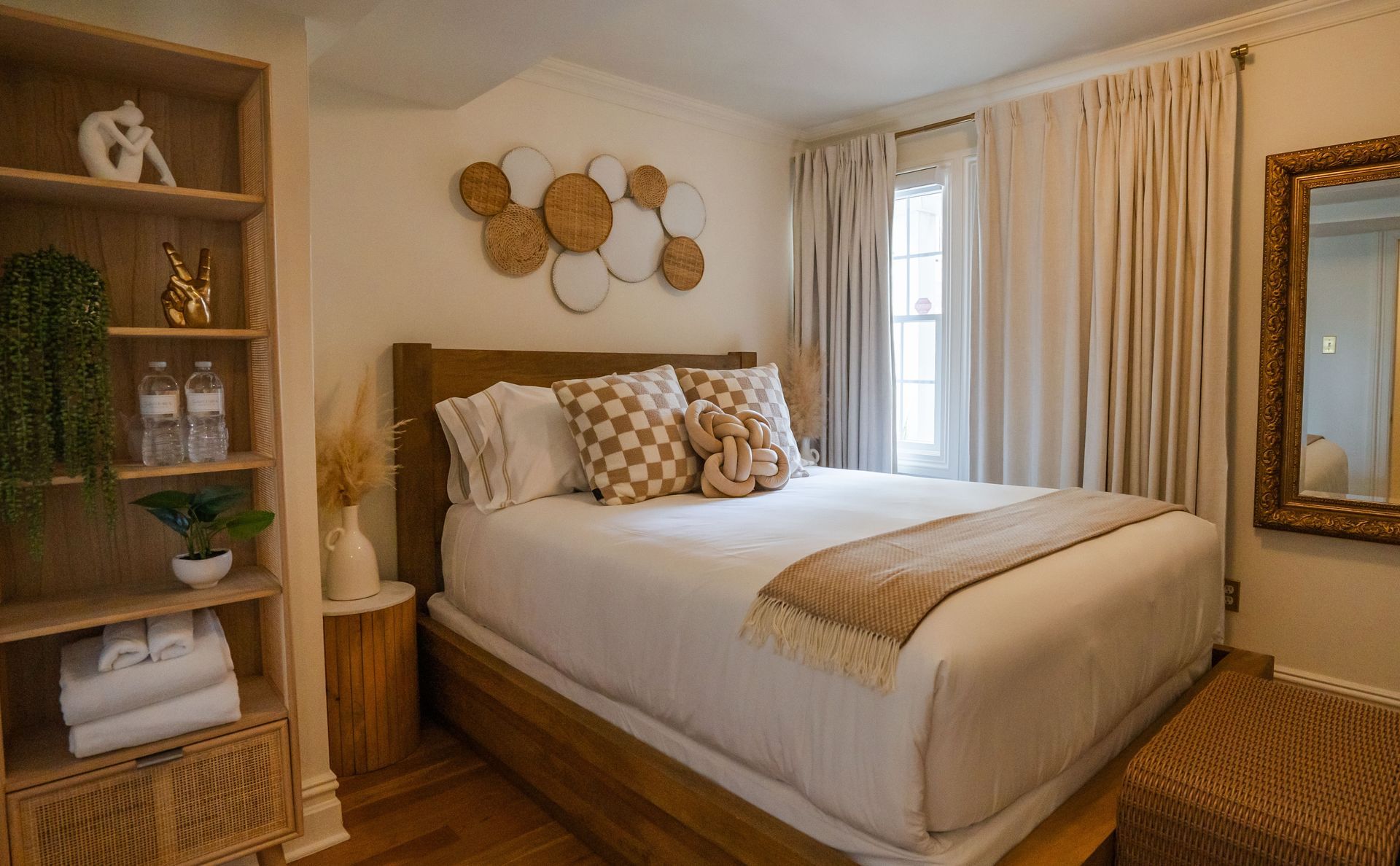 Cozy bedroom with a bed, bookshelf, and decorative wall art. Light colors and natural wood accents.