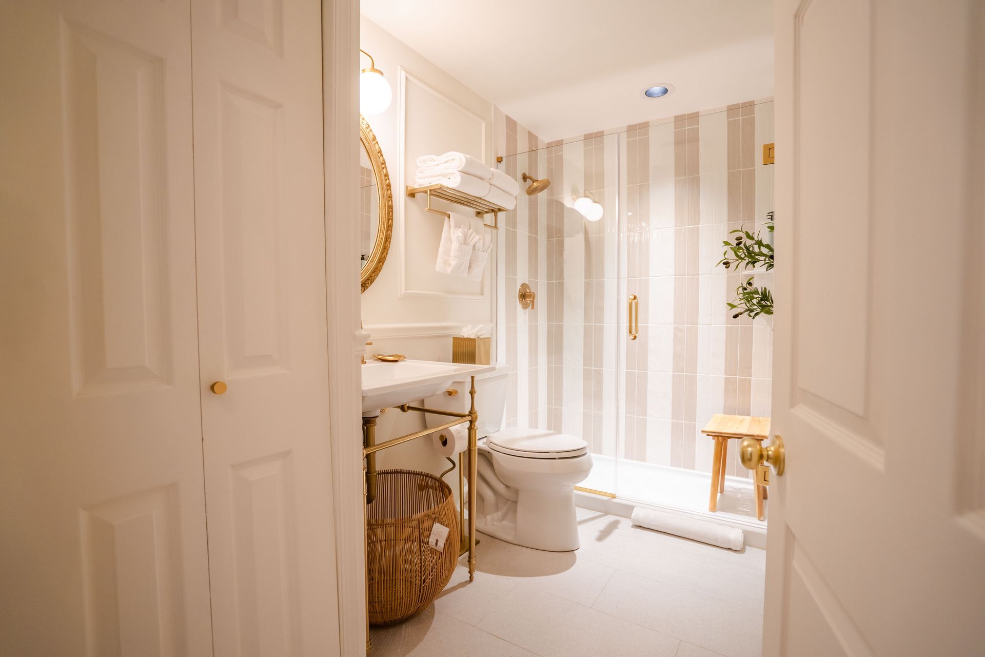 Bathroom interior with white and gold accents, including a toilet, shower, and sink.