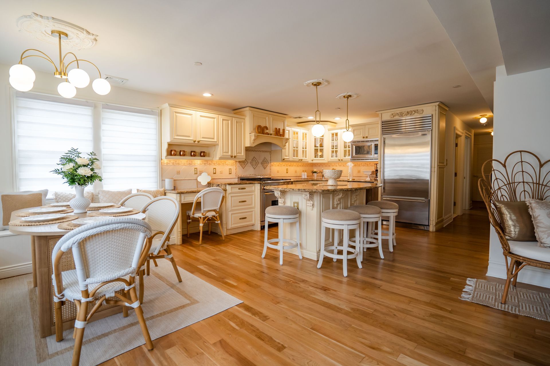 Bright kitchen with light wood floor, white cabinets, and a dining table set near a window.