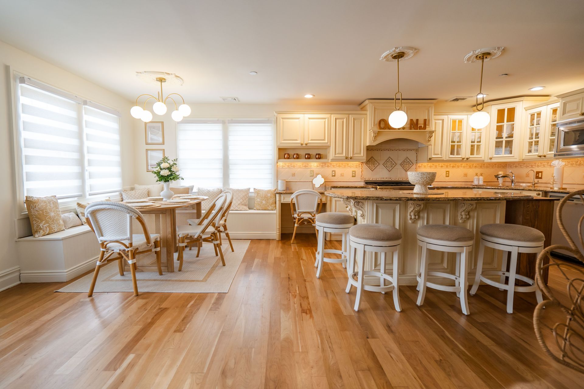 Spacious kitchen with wood floors, white cabinets, and a dining area with a table and bench seating.