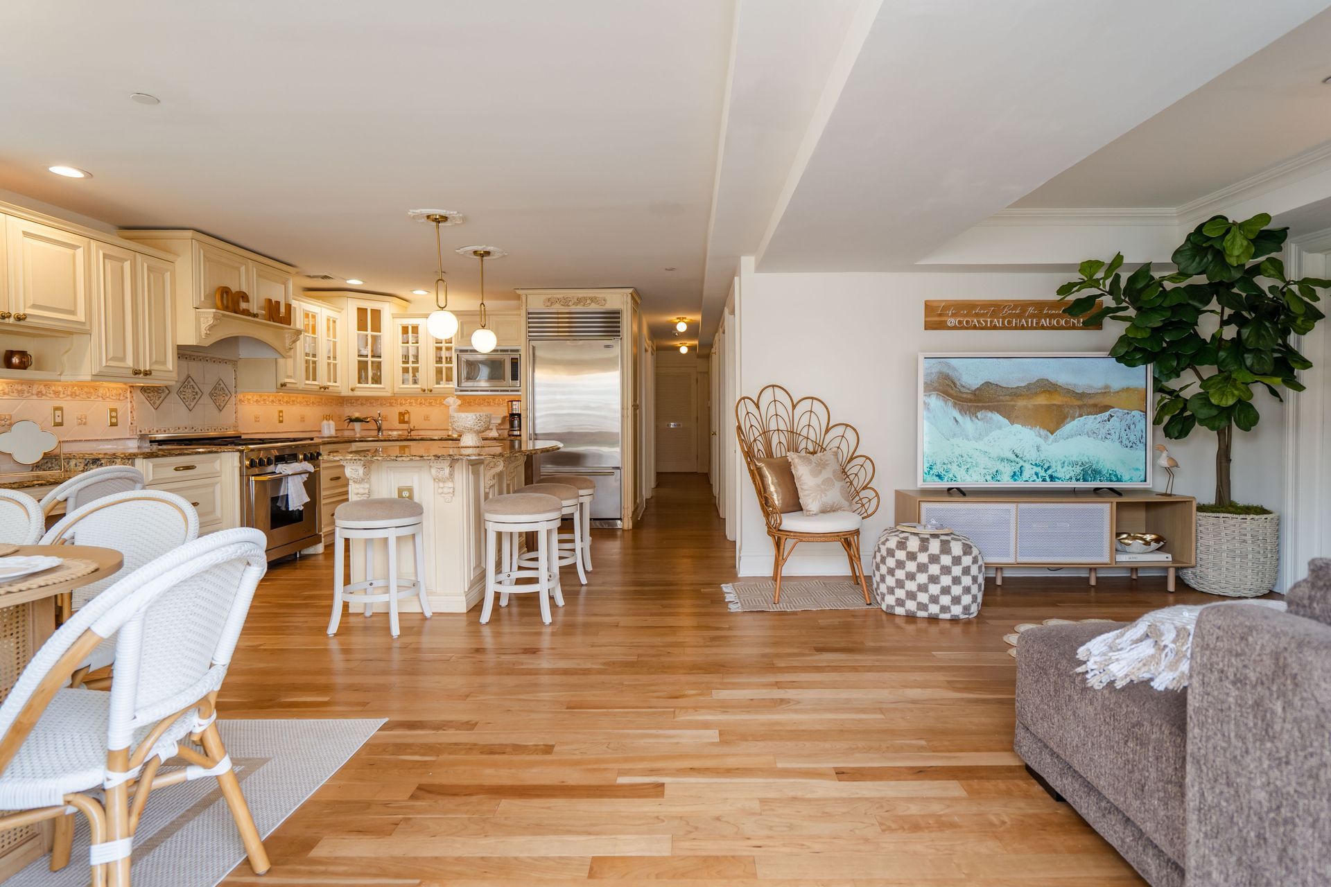 Open-concept kitchen and living area with hardwood floors, white cabinets, and a beige sofa.