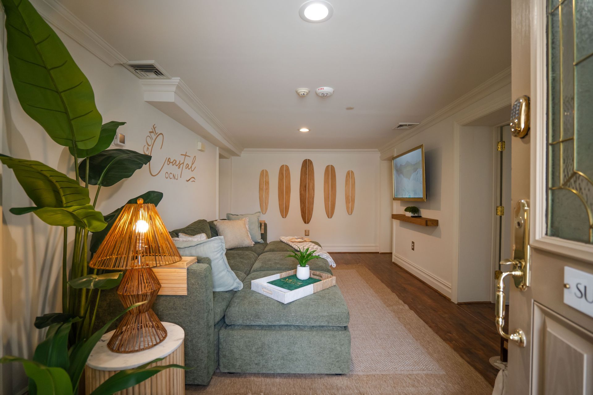 Cozy living room with green sectional sofa, surfboard wall decor, and a television.