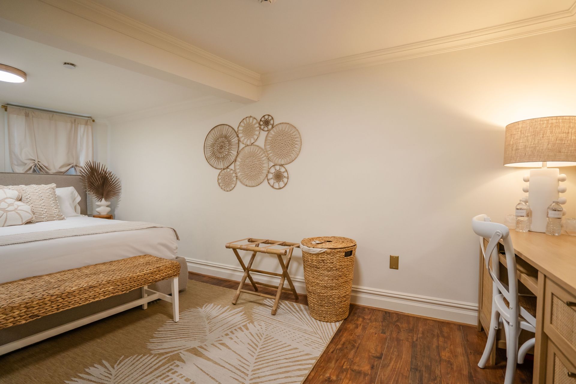 Bedroom with a light color scheme. Features a bed, desk, and decorative wall art.