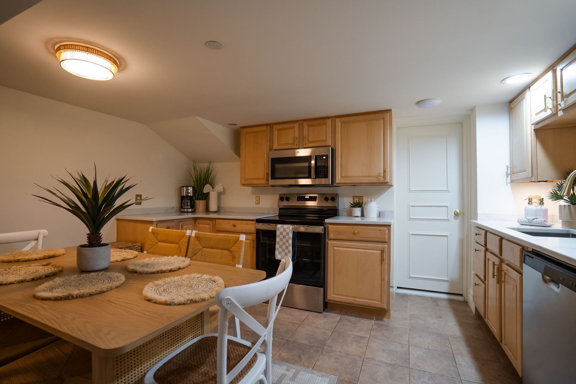 Kitchen with wooden cabinets, stainless steel appliances, dining table set for a meal.