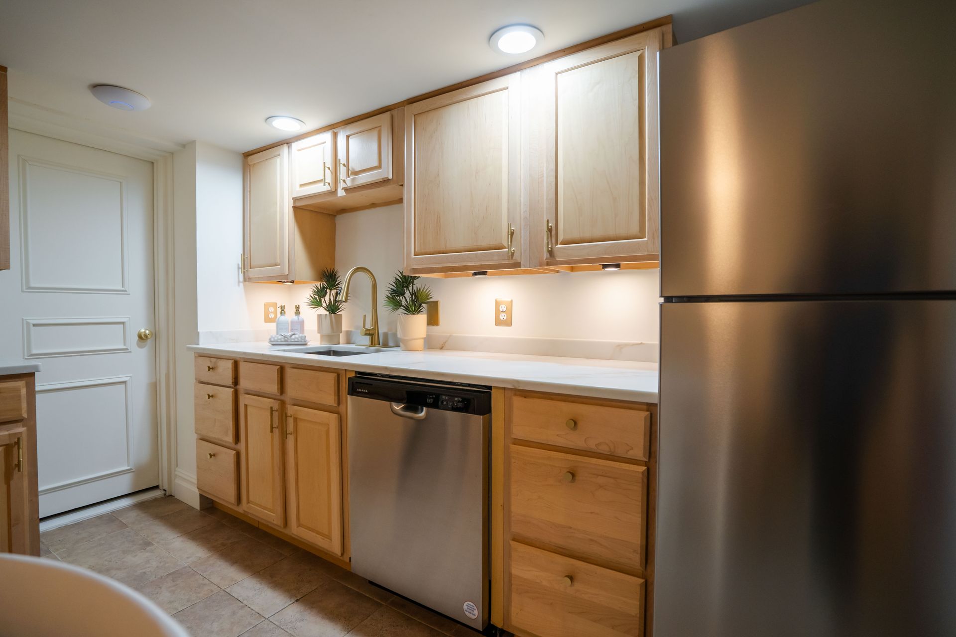 Kitchen with light wood cabinets, stainless steel appliances, and a white countertop.