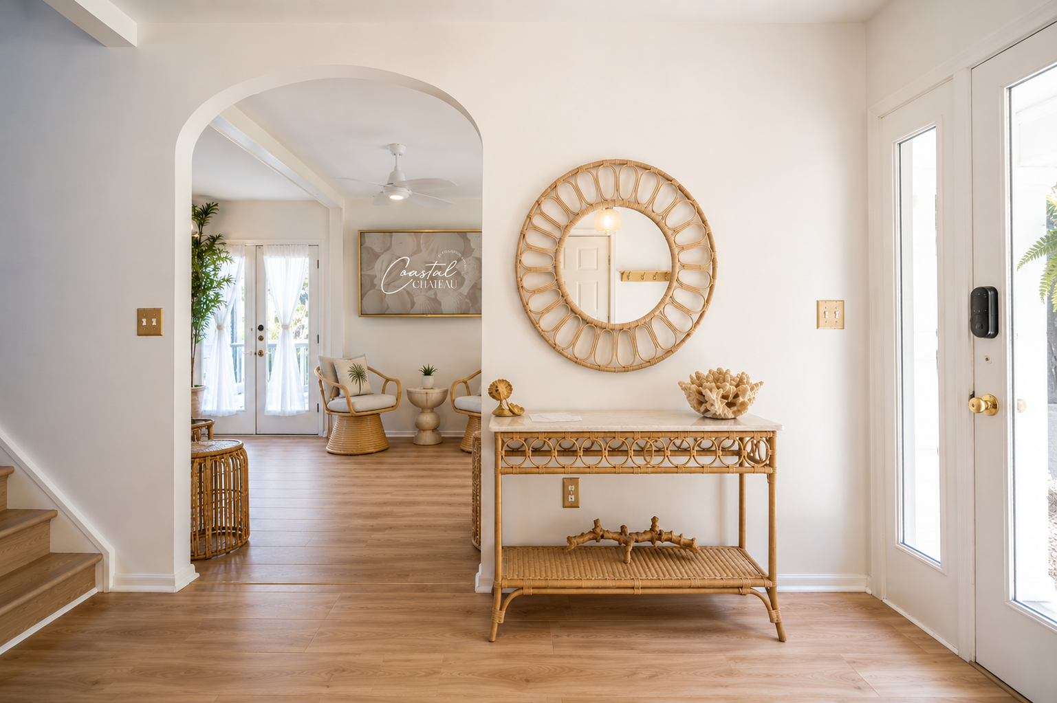 Bright entryway with arched doorway, gold console table, round mirror, and white double doors