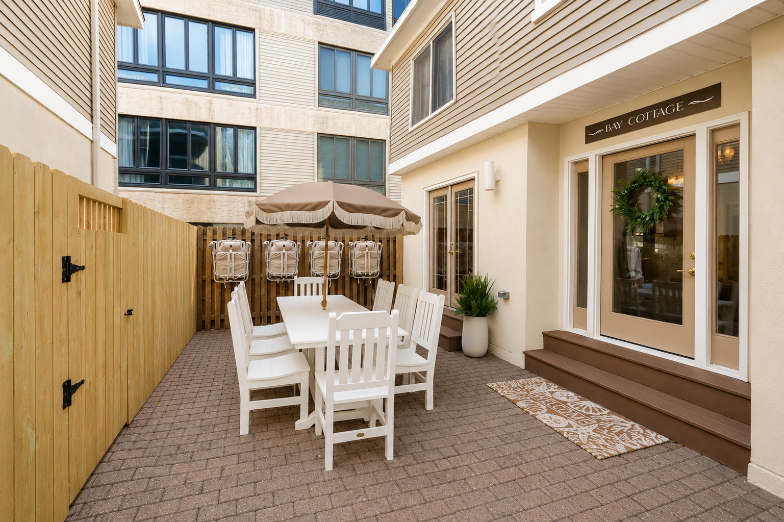 Patio courtyard with white dining set, pergola, and beige townhouse walls