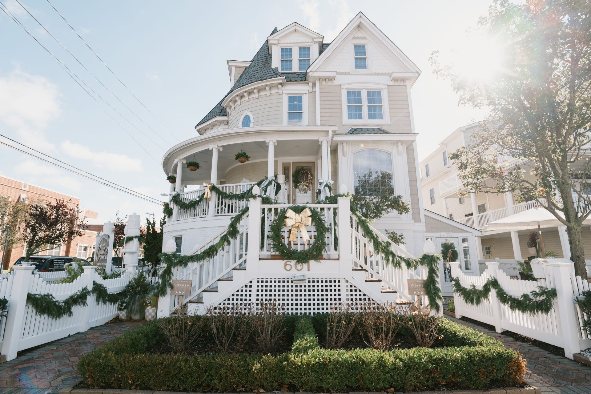 Three-story Victorian home with white trim and holiday greenery.