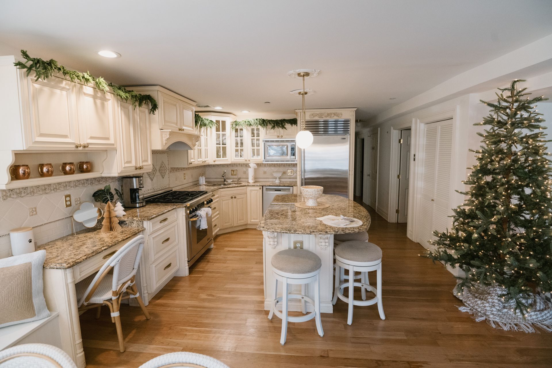 Kitchen decorated for Christmas with garland, tree, and neutral decor.