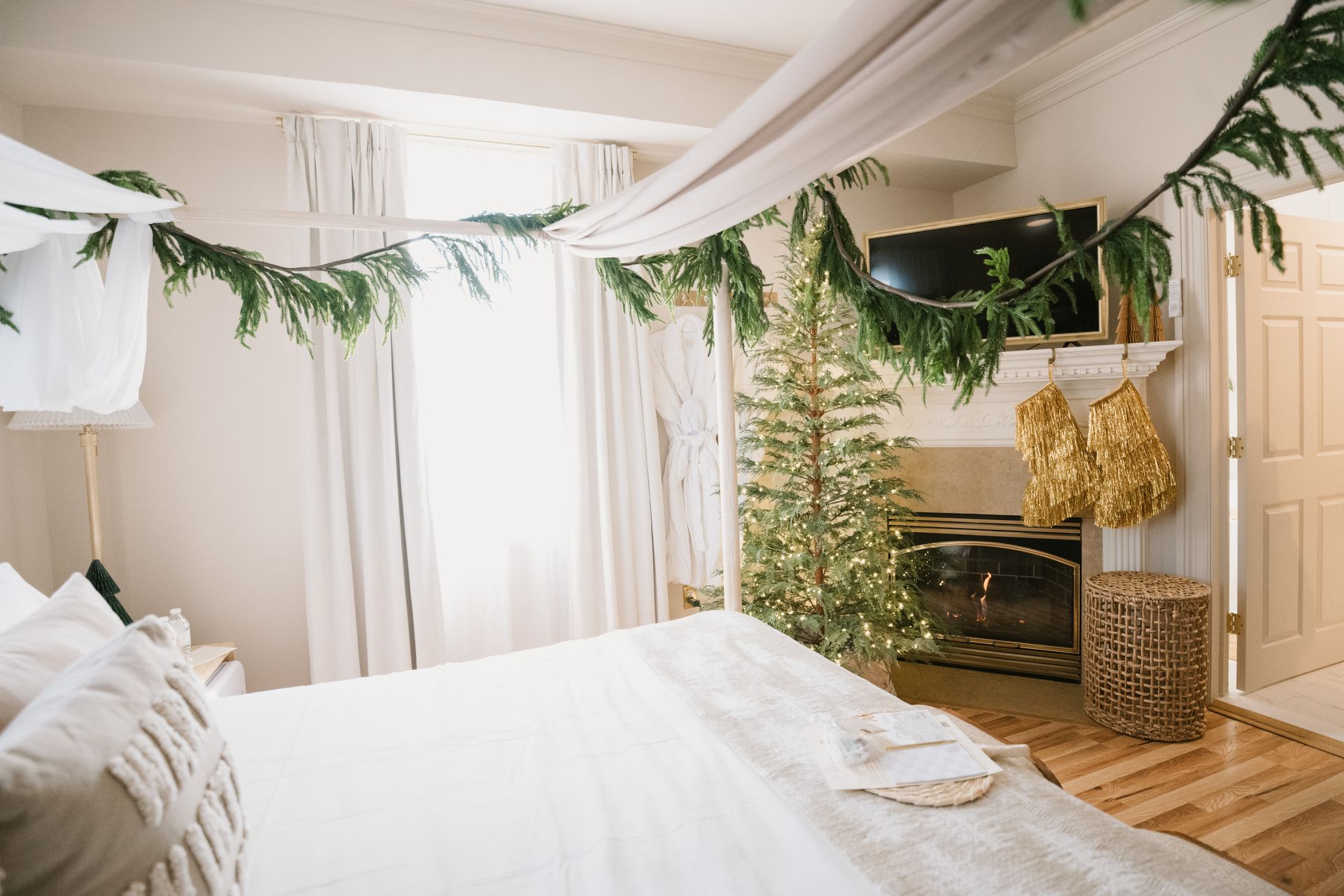 Bedroom decorated for Christmas with a bed, tree, garland, and fireplace.