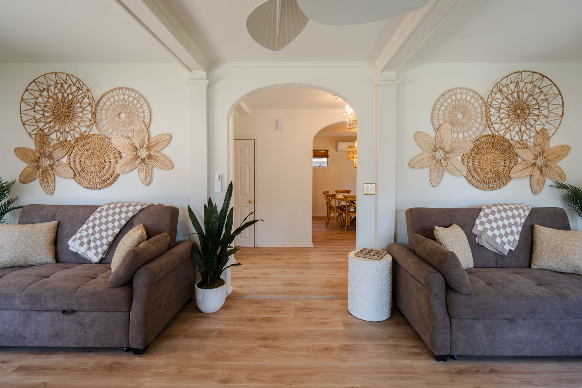 Cozy living room with two gray sofas, woven wall decor, and a white arched doorway on wood floors