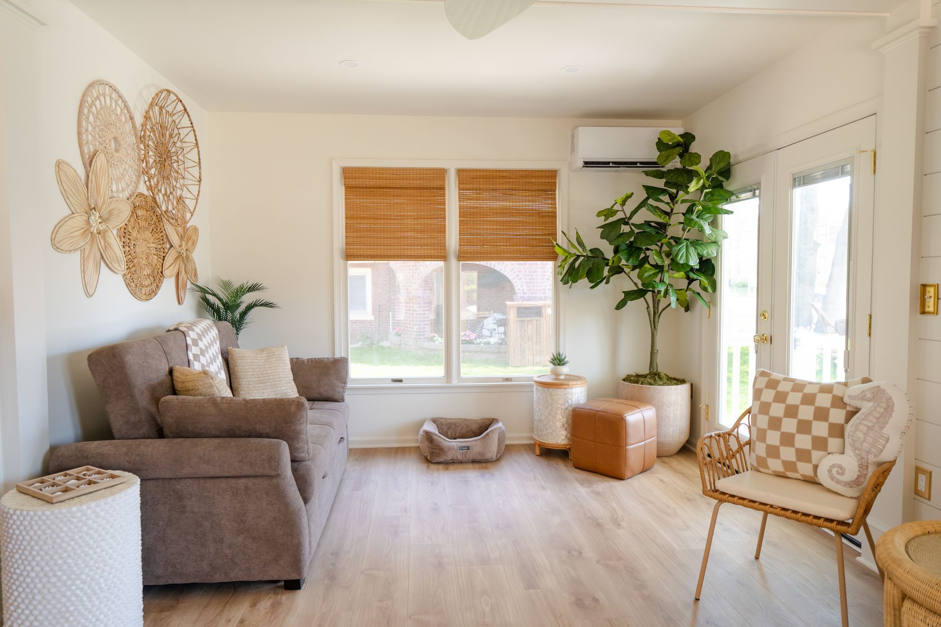 Bright, airy living room with beige sofa, woven decor, plants, and large windows with bamboo shades