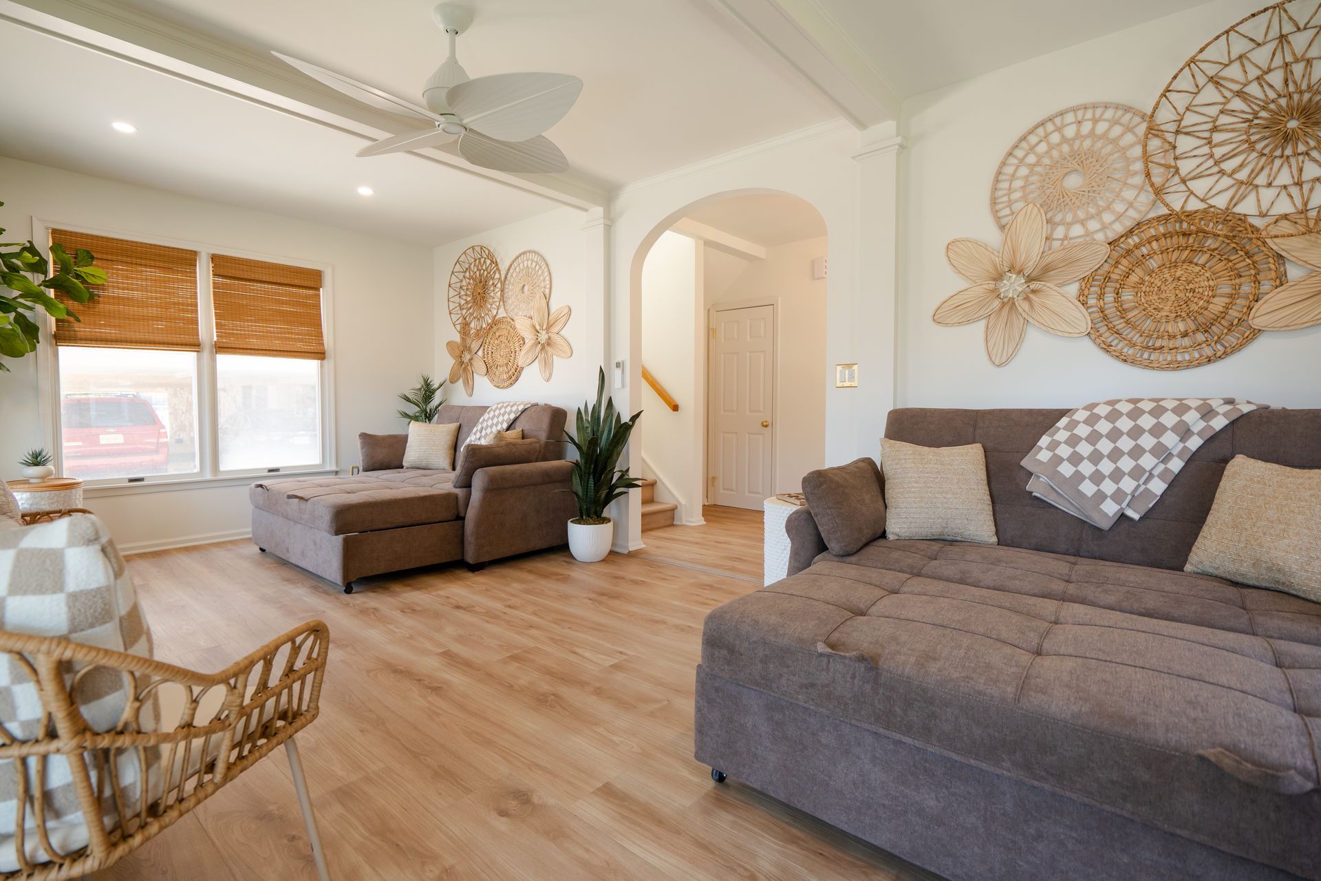 Bright living room with gray sofas, wood floors, wall decor, and sunlight through large windows