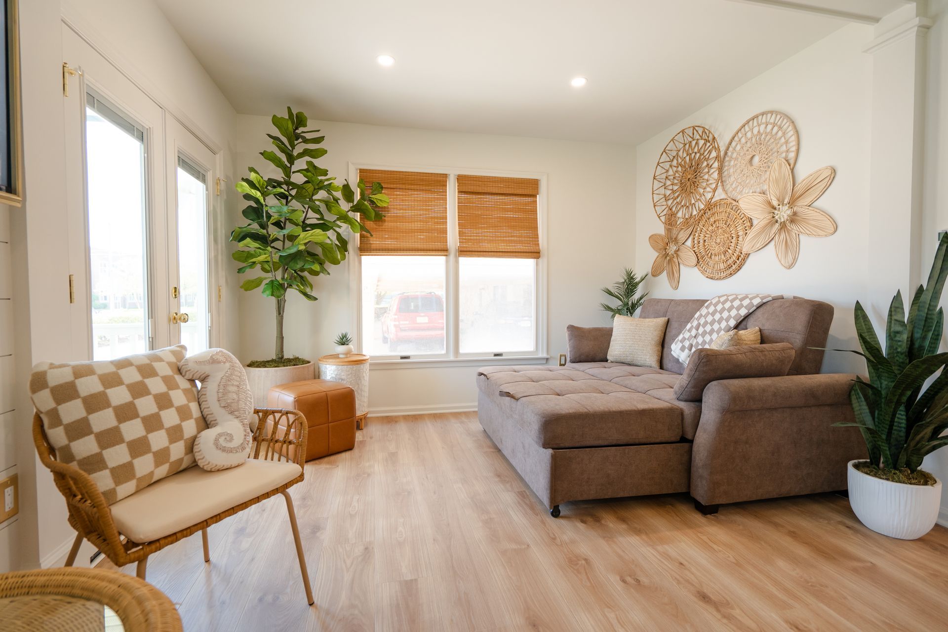Bright modern living room with gray sectional, wicker chair, plants, and woven wall decor