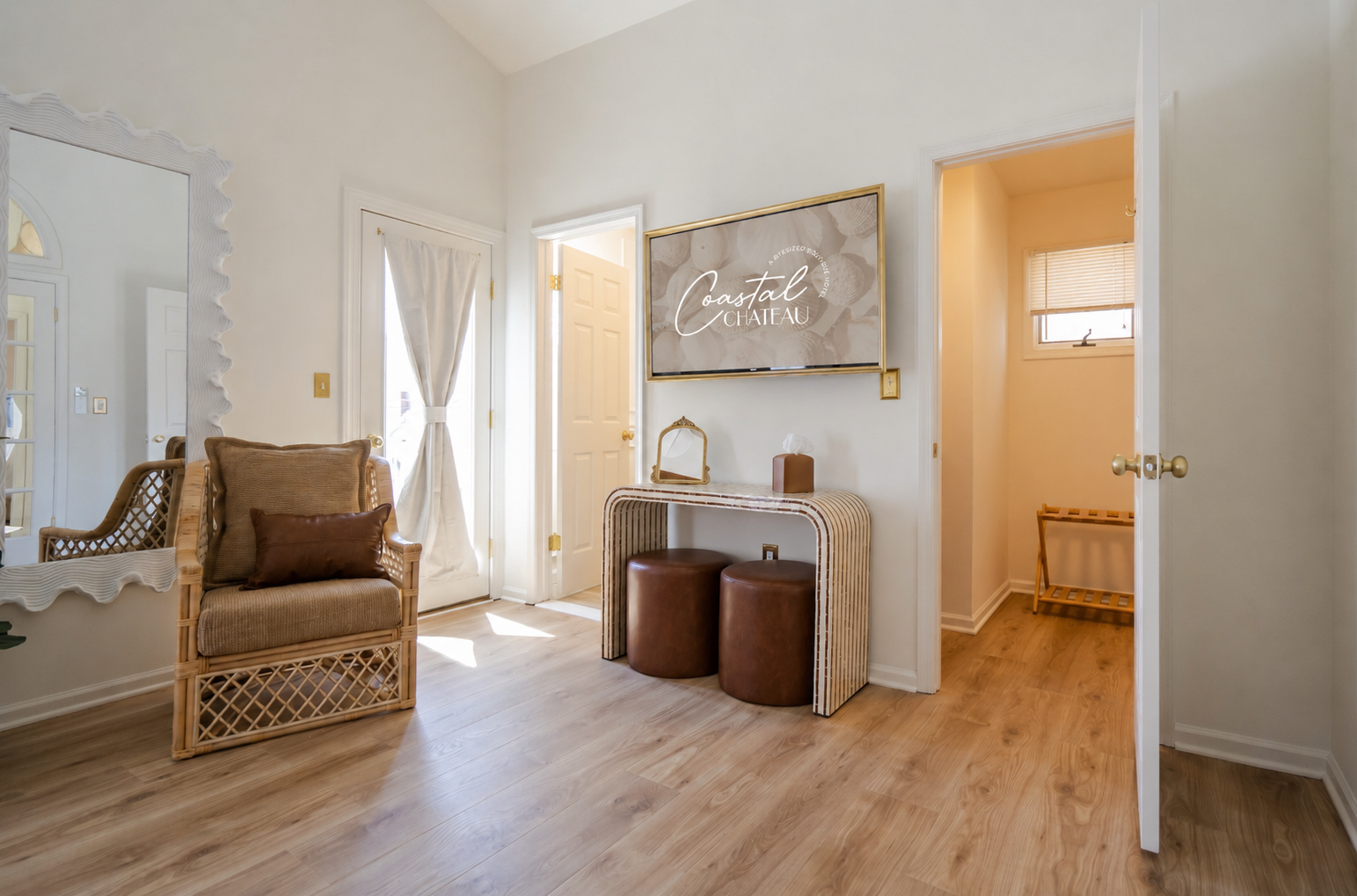 Bright hallway with wicker chair, vanity table, mirror, and open doors to adjoining rooms.
