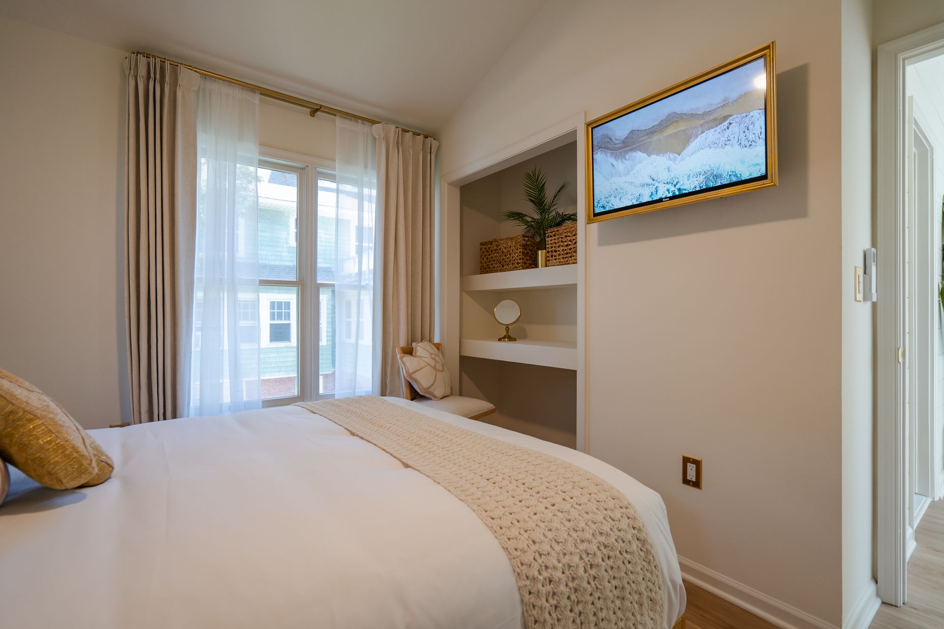 Bright bedroom with bed, window, wall shelves, and framed artwork